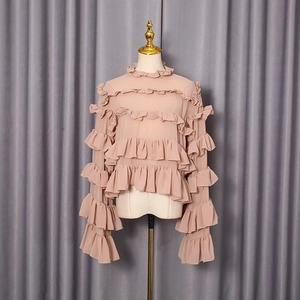Detail of ruffle layers on a dusty pink chiffon shirt with elegant pleats and textures