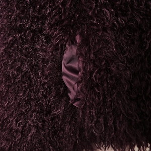 Close-up of deep burgundy curly faux fur texture with silky smooth satin lining detail