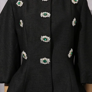 Dettaglio di una camicia nera con eleganti bottoni in smeraldo e strass luminosi