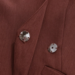 Macro shot of silver metal snap buttons on twill fabric of a dark brick red blazer