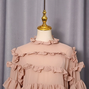 Close-up of pink chiffon blouse featuring layered ruffles and a delicate ruffle stand collar