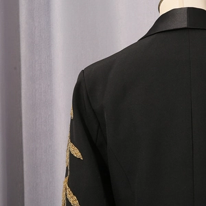 Détail de la broderie dorée sur un blazer noir avec revers en satin pour un style chic