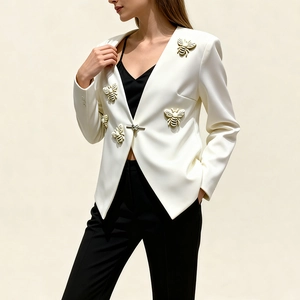 Détail du blazer blanc orné d'abeilles 3D avec une boucle métallique de fermeture
