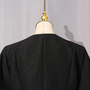 Vista posteriore dei dettagli del tessuto in tweed nero e del colletto della giacca da donna