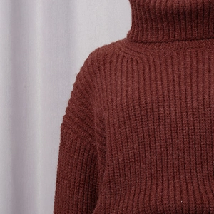 Gros plan du pull à col roulé bordeaux avec texture en maille côtelée de haute qualité