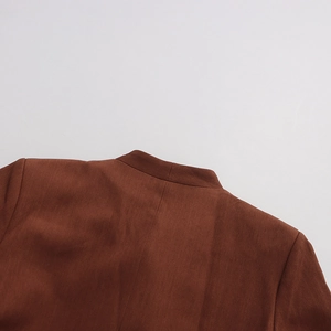 Close-up of the neat stitching and fine fabric texture on a reddish-brown blazer collar