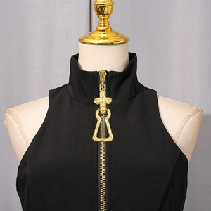 Detail view of high collar black top with decorative gold zipper and embossed slider