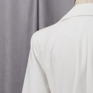 Gros plan sur la couture de l'épaule et la texture du tissu blanc du manteau chic pour femme
