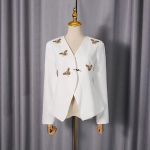 Détail du blazer blanc avec écussons d'abeilles dorées en strass et nœud papillon