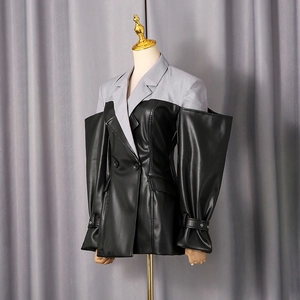 Detail of patchwork blazer with grey fabric collar and black faux leather sleeves on mannequin