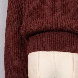 Détail d'un pull en maille épaisse bordeaux montrant la texture côtelée sur un mannequin