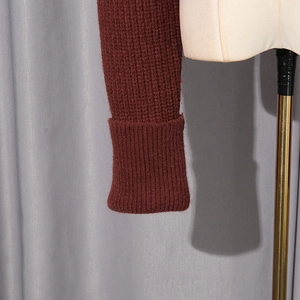 Détail de la manche d'un pull rouge vin avec tricot gaufré et poignets côtelés
