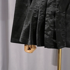 Vue macro d'un tissu plissé noir satiné sur un mannequin de couture professionnel