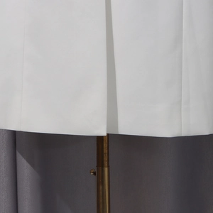 Vue détaillée de l'ourlet du trench-coat blanc avec coutures nettes et fente