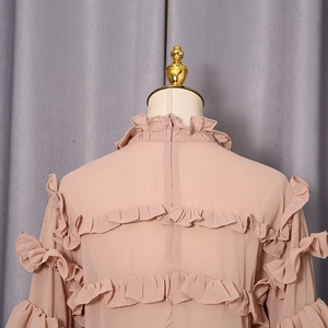 Detail of ruffle layers and invisible zipper on the back of a lotus pink chiffon shirt