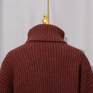 Détail d'un pull à col roulé bordeaux avec une texture en maille côtelée verticale