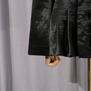 Gros plan détaillé du tissu satiné plissé noir brillant d'un blazer ou d'une jupe