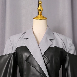 Detailed view of women's gray suit jacket with black faux leather patchwork and wide lapels