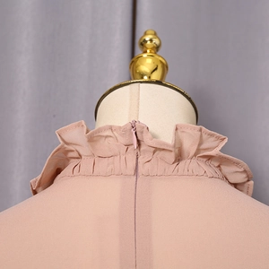 Close-up of pink ruffle high collar shirt with invisible back zipper detail on mannequin