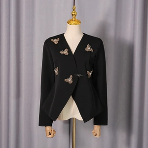 Détail d'un blazer noir cintré avec boucles papillon argentées et patchs d'abeilles en cristal