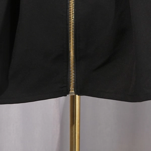 Detail of a high-quality gold metal zipper on a sexy black dress with premium texture
