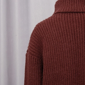 Détail rapproché d'un pull à col roulé bordeaux avec texture tricotée à côtes verticales