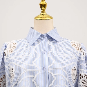 Detailed view of striped shirt featuring intricate white lace patchwork on shoulders