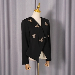 Détail d'un blazer noir chic orné de broches abeilles dorées en 3D avec des strass brillants
