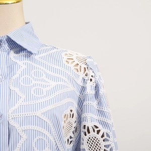 Detail of blue and white striped shirt featuring intricate white lace cutout on shoulder