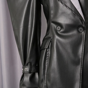Detail of black leather blazer showing double-breasted design and eyelet strap cuffs
