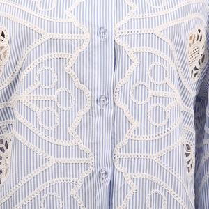 Detail of blue striped shirt with white hollow lace embroidery and clear buttons