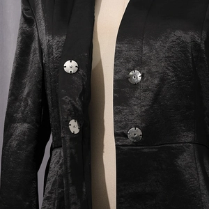 Détail de boutons-pression argentés sur un blazer noir texturé avec un éclat subtil