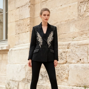Detailed close-up of intricate crystal wing embroidery on a black wool blazer jacket