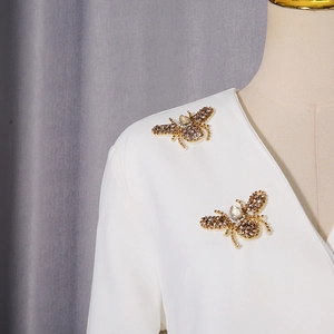 Détail de broches abeilles faites main avec sequins et strass sur une veste blazer