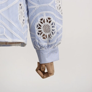 Detailed close-up of blue striped shirt cuff with delicate white lace embroidery