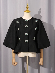 Elegante giacca nera corta con bottoni gioiello color smeraldo e ampie maniche a svasate