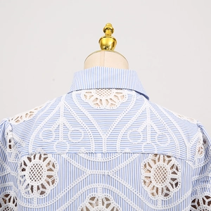 Detailed close-up of white floral lace cutout on a light blue striped summer shirt