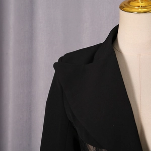 Detail view of black blazer with lace hem showing shoulder structure and notched lapel