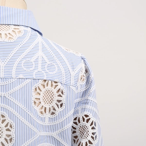Detail of blue striped shirt with white floral hollow lace embroidery on the shoulder
