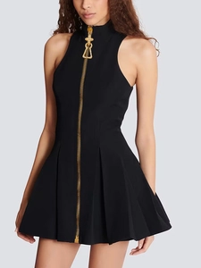 Chic black sleeveless mini dress with high neck and prominent gold zipper front detail