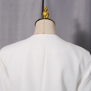 Détail du dos d'un blazer blanc minimaliste montrant le col rond et la couture centrale