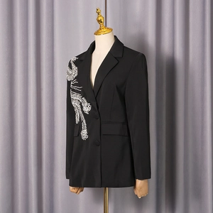 Détail de la broderie plume argentée et des boutons croisés sur le blazer noir femme