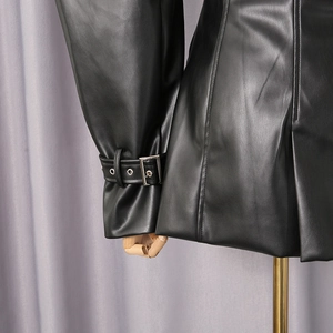 Detail of black faux leather blazer featuring silver metal buckles and adjustable sleeve straps