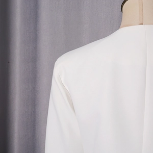 Vue détaillée de l'épaule d'un blazer blanc avec épaulettes et texture de tissu premium