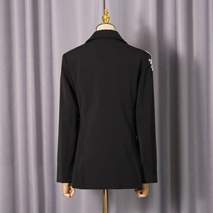 Détail du dos d'un blazer noir avec broderie élégante en paillettes sur l'épaule droite