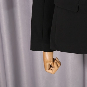 Close-up of black mesh blazer sleeve and side pocket detail on a wooden mannequin