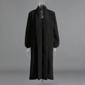 Macro shot of the black quilted texture and glossy finish on this long winter coat