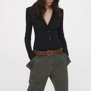Detail of slim-fit double-breasted black blazer with shoulder pads and deep V-neck