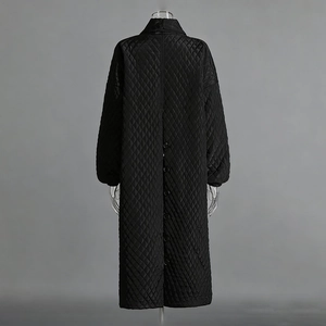 Detail of women's black quilted long coat featuring back button slit and diamond pattern