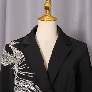 Détail d'un blazer noir élégant avec broderie complexe de plumes de phénix en strass argentés
